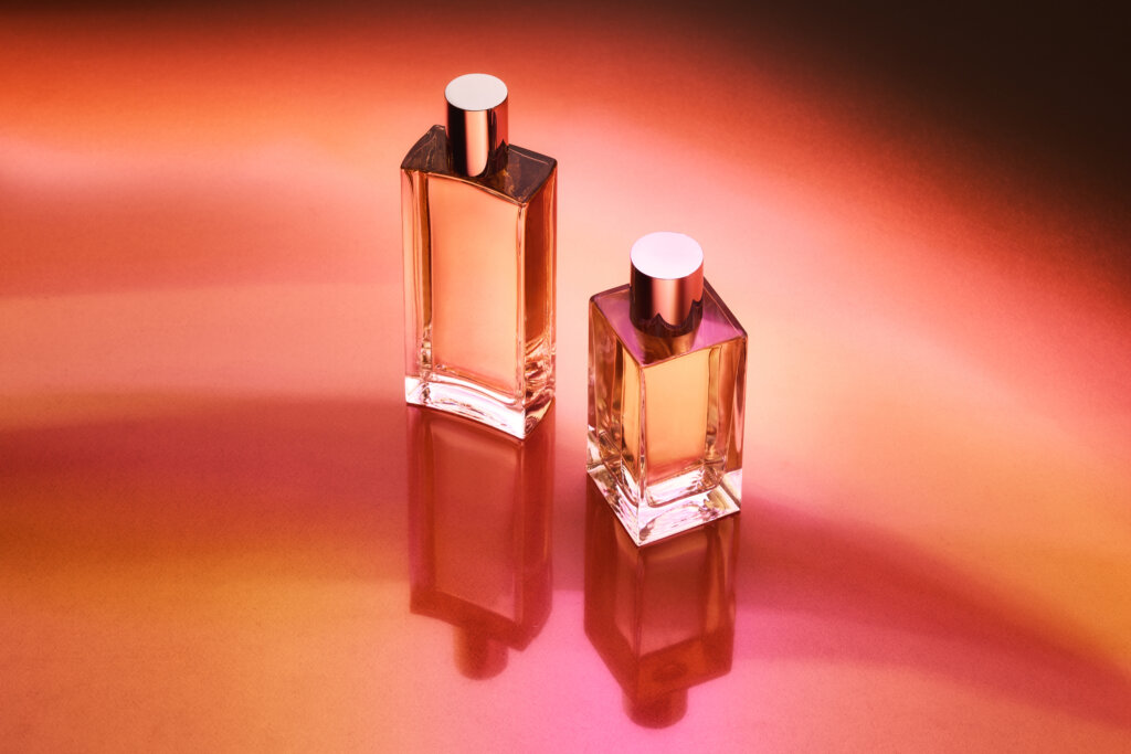 two perfume bottles on red and orange background shot from the top