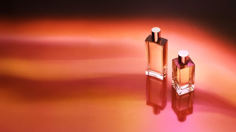 two perfume bottles on red and orange background shot from the top